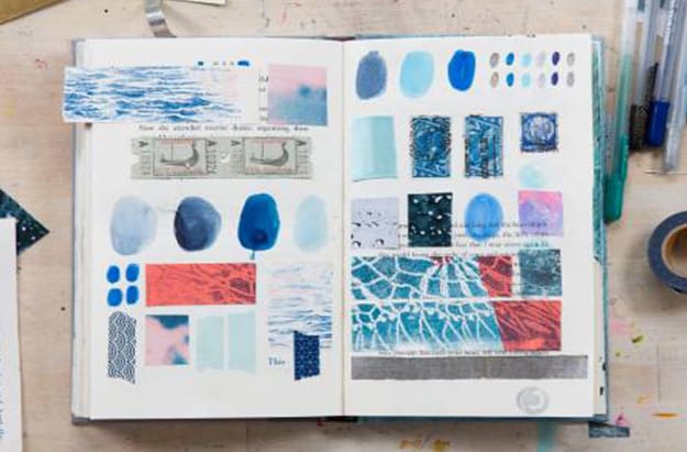 Open Book with Paintings Surrounded by Various Art Supplies