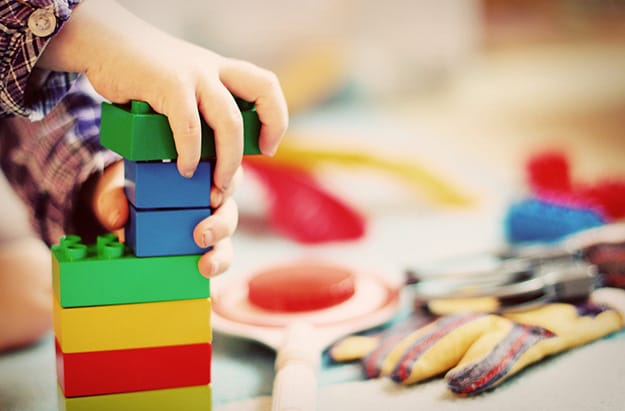 Hand of Child Gripping and Stacking Blocks